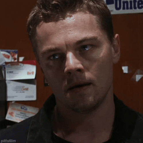 A Man Is Looking At The Camera With A Unite Sign In The Background GIF