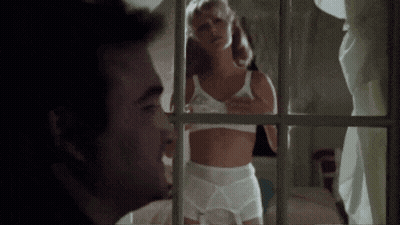 A Man Is Looking Out A Window At A Woman In Lingerie . GIF