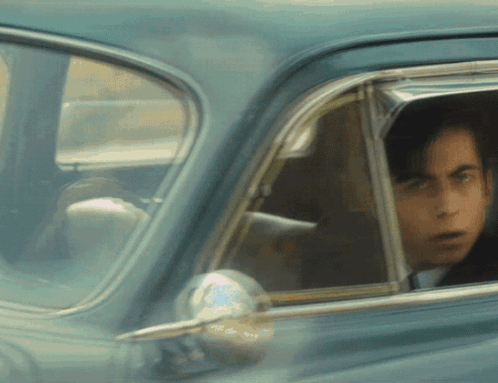 A Man Is Looking Out Of A Car Window GIF