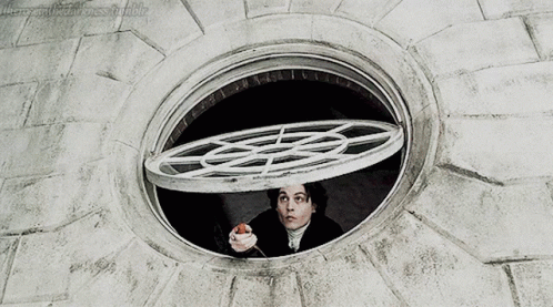 A Man Is Looking Out Of A Round Window With A Circular Grid On It GIF