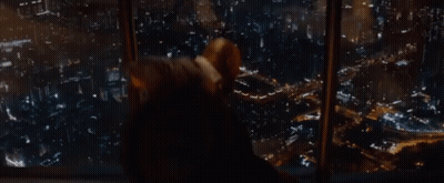 A Man Is Looking Out Of A Window At A City GIF