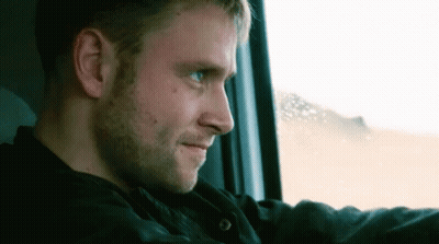 A Man Is Looking Out Of A Window While Driving A Car . GIF