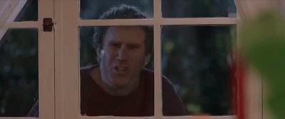 A Man Is Looking Out Of A Window With A Serious Look On His Face . GIF