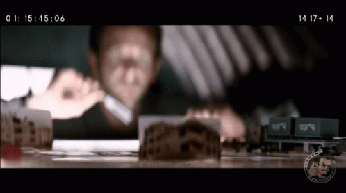 A Man Is Looking Through A Magnifying Glass At A Model Train Set GIF