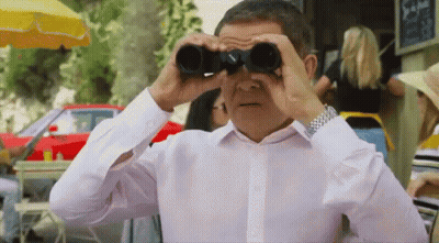 A Man Is Looking Through Binoculars In A Restaurant . GIF