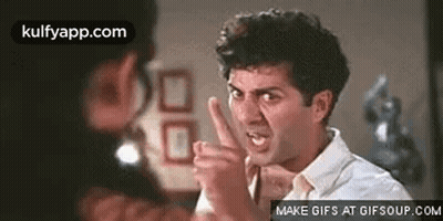 A Man Is Making A Funny Face And Pointing His Finger At Another Man . GIF