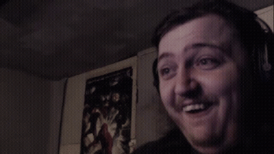 A Man Is Making A Funny Face In A Dark Room . GIF