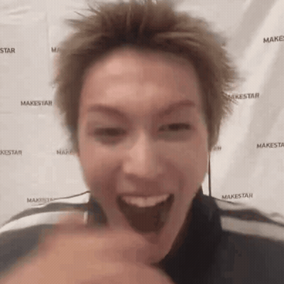 A Man Is Making A Funny Face In Front Of A Makestar Backdrop . GIF