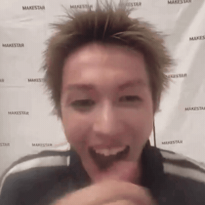 A Man Is Making A Funny Face In Front Of A Makestar Banner . GIF