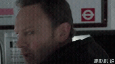 A Man Is Making A Funny Face In Front Of A Sign That Says E On It . GIF