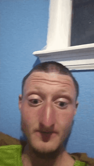 A Man Is Making A Funny Face In Front Of A Window GIF