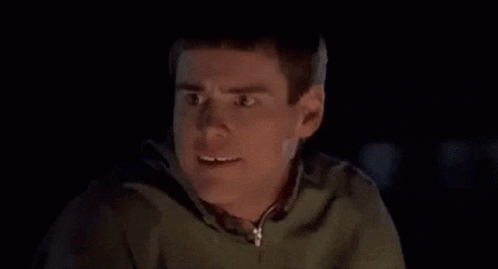 A Man Is Making A Funny Face In The Dark While Wearing A Green Hoodie . GIF