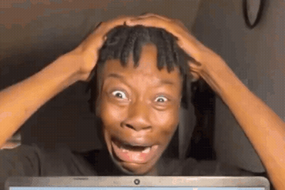 A Man Is Making A Funny Face While Looking At A Laptop Computer . GIF