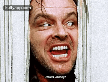 A Man Is Making A Funny Face While Looking Through A Hole In The Wall . GIF