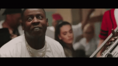 A Man Is Making A Funny Face While Playing A Trumpet In Front Of A Crowd . GIF