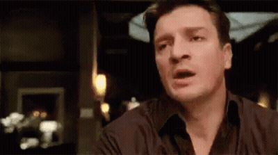 A Man Is Making A Funny Face While Sitting At A Table . GIF