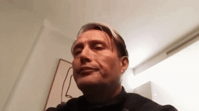 A Man Is Making A Funny Face While Sitting In A Chair In A Room . GIF