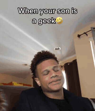 A Man Is Making A Funny Face While Sitting On A Couch With The Caption When Your Son Is A Geek GIF
