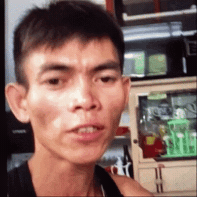 A Man Is Making A Funny Face While Standing In Front Of A Kitchen Counter . GIF