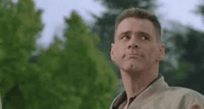 A Man Is Making A Funny Face While Standing In Front Of A Tree . GIF