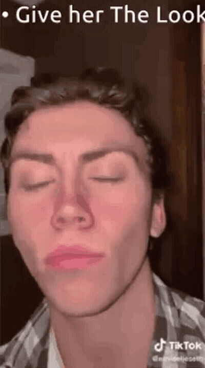 A Man Is Making A Funny Face With His Eyes Closed And His Nose Is Red . GIF
