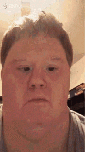 A Man Is Making A Funny Face With His Eyes Closed . GIF