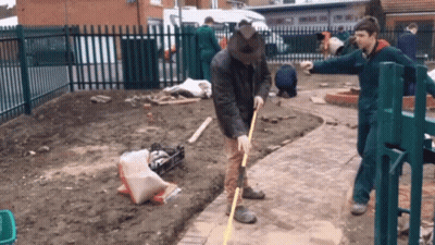 A Man Is Measuring The Ground With A Yellow Tape Measure GIF