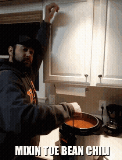 a man is mixing bean chili in a pot