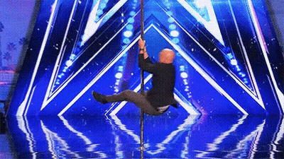 A Man Is On A Pole On A Stage With A Blue Background GIF