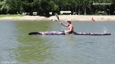 A Man Is Paddling A Purple Kayak On A Lake With A Canoesport Logo In The Corner GIF