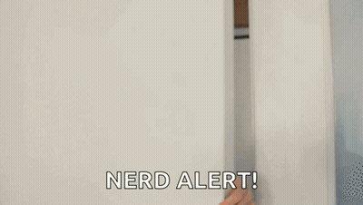 A Man Is Peeking Out From Behind A White Wall And Saying `` Nerd Alert '' . GIF