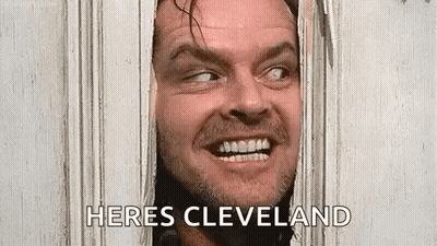 A Man Is Peeking Through A Hole In A Door And Smiling . GIF