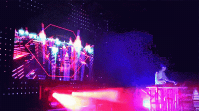 A Man Is Playing A Dj Set In Front Of A Large Screen With A City In The Background GIF
