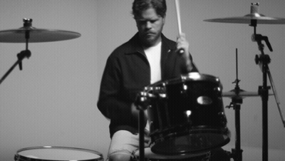 A Man Is Playing A Drum Set With A Sabian Cymbal In The Background GIF