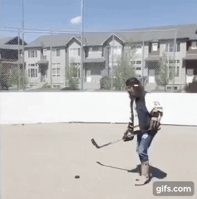 A Man Is Playing A Game Of Ice Hockey On A Concrete Rink . GIF