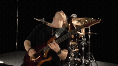 A Man Is Playing A Guitar And A Woman Is Playing Drums In A Band . GIF