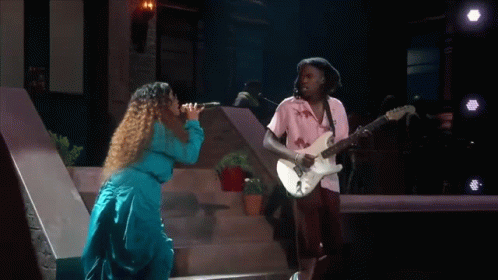 A Man Is Playing A Guitar And A Woman Is Singing . GIF