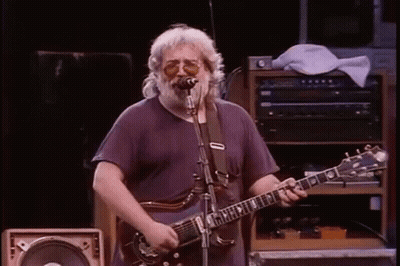 A Man Is Playing A Guitar And Singing Into A Microphone . GIF