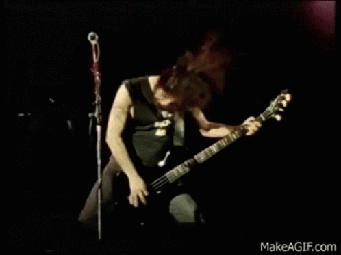 A Man Is Playing A Guitar And Singing Into A Microphone On Stage . GIF