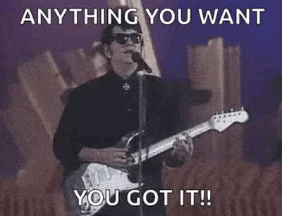 A Man Is Playing A Guitar And Singing Into A Microphone While Standing On A Stage . GIF