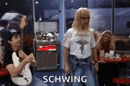 A Man Is Playing A Guitar In A Diner While Another Man Is Dancing . GIF