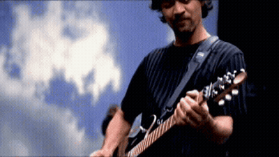 A Man Is Playing A Guitar In Front Of A Blue Sky GIF