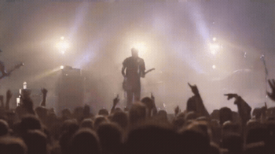 A Man Is Playing A Guitar In Front Of A Crowd Of People GIF