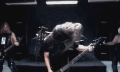 A Man Is Playing A Guitar In Front Of A Drum Set While Another Man Plays Drums GIF