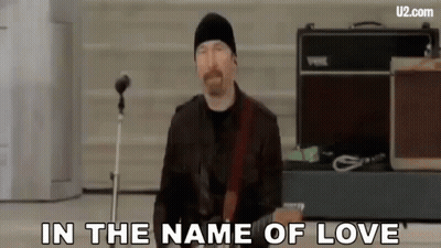 A Man Is Playing A Guitar In Front Of A Microphone And Singing . GIF