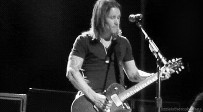 A Man Is Playing A Guitar In Front Of A Microphone . GIF