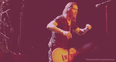 A Man Is Playing A Guitar In Front Of A Microphone With The Words Lizzie Is The Topbanana Written Below Him GIF