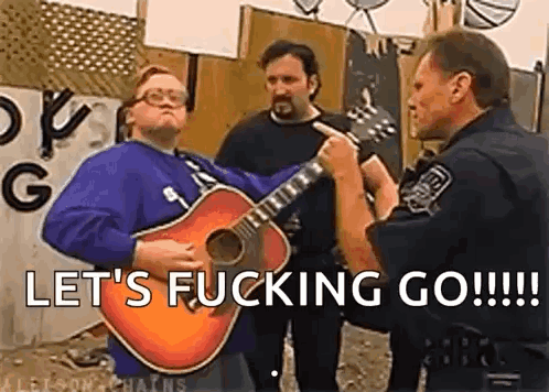 A Man Is Playing A Guitar In Front Of A Police Officer While Another Man Looks On . GIF