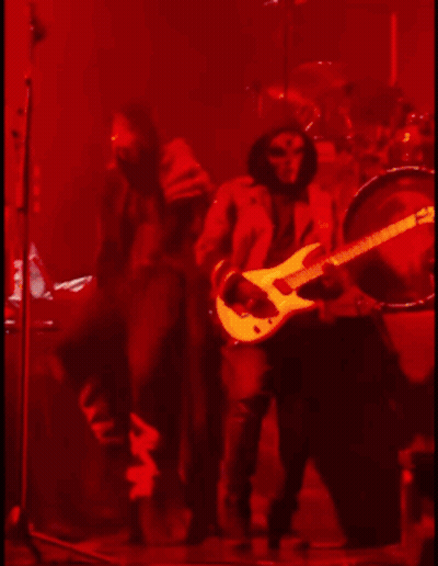 A Man Is Playing A Guitar On A Stage In A Dark Room GIF