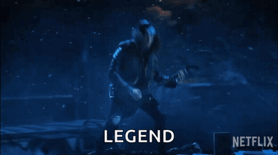 A Man Is Playing A Guitar On A Stage In Front Of A Crowd And The Word Legend Is On The Screen . GIF